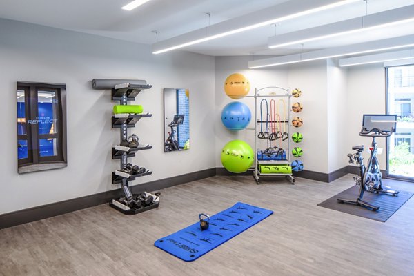 Fitness room with modern exercise equipment including dumbbells and a stationary bike