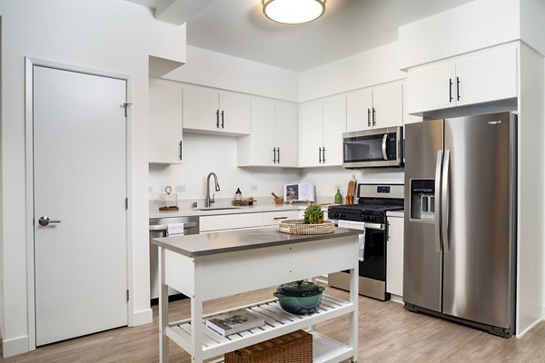 Modern kitchen with stainless steel appliances and island at Aston at Gateway Apartments