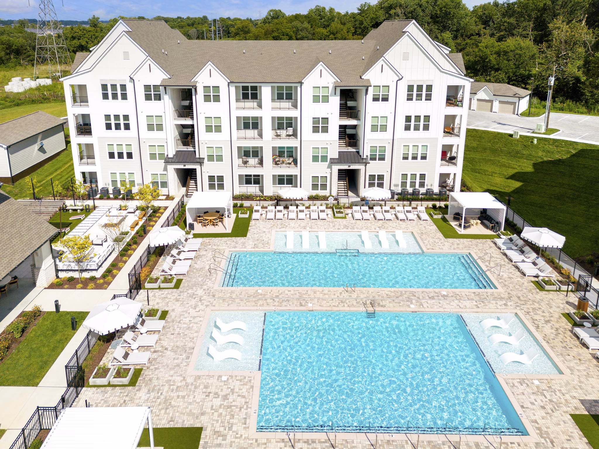 Elegant outdoor pool area at Maxwell Apartments with luxurious lounge chairs and scenic views