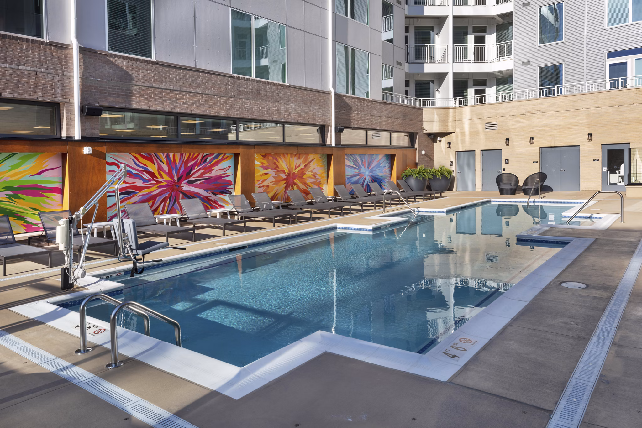 Contemporary pool at The Blake Apartments featuring resort-style loungers and lush landscaping