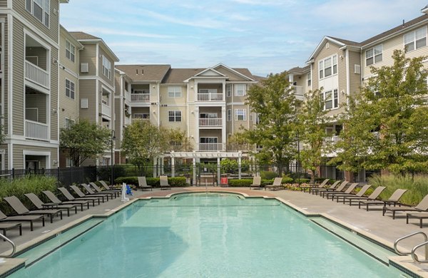 Rooftop pool with lounge chairs and umbrella at The Avens Dedham Station Apartments