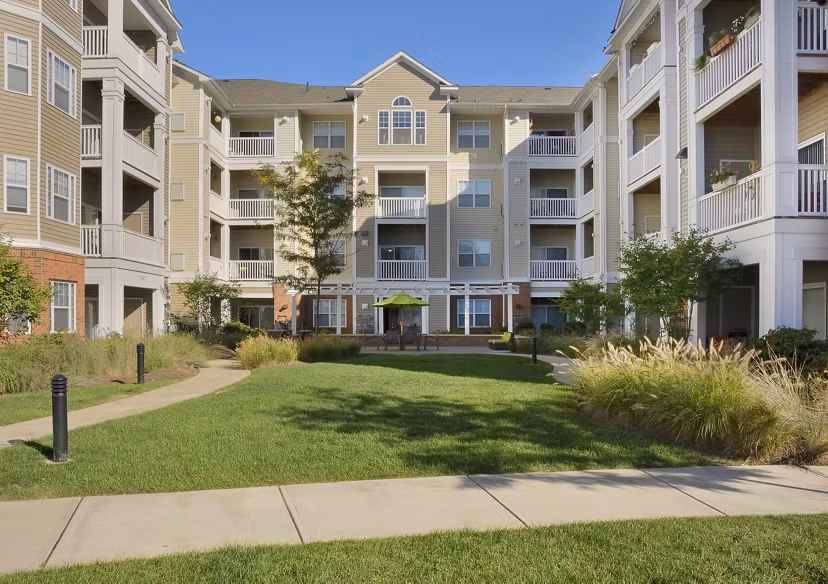 Courtyard with landscaped garden and seating area at The Avens Dedham Station Apartments