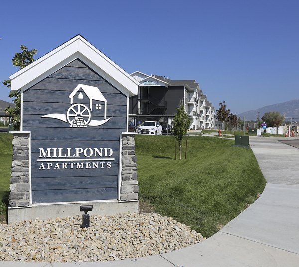 Millpond Apartments: Community signage surrounded by lush greenery and modern architecture