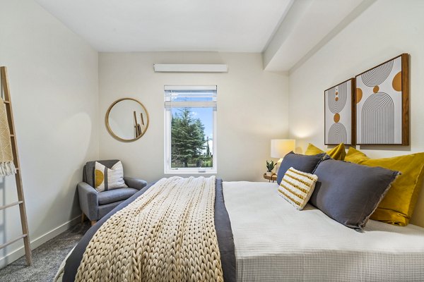 Modern bedroom featuring cozy decor and natural light at The Oliveen Apartments