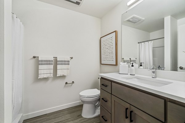 Modern bathroom featuring marble countertops and sleek fixtures at The Oliveen Apartments