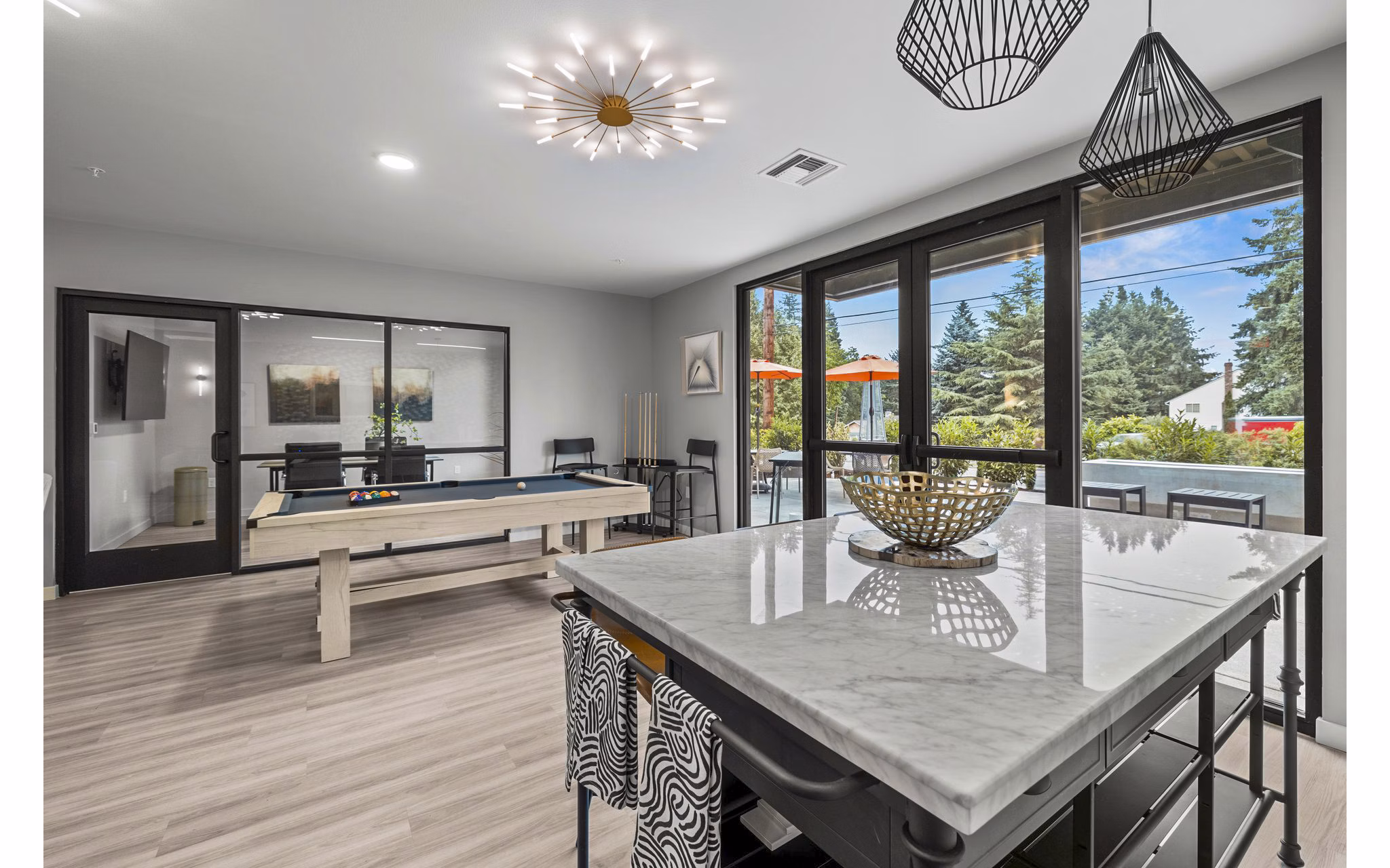 Vibrant clubhouse game room with pool table and lounge seating at The Oliveen Apartments