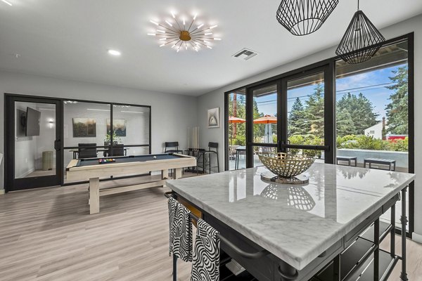 Vibrant clubhouse game room with pool table and lounge seating at The Oliveen Apartments