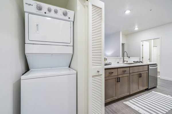 Modern laundry room with energy-efficient washers and dryers at The Oliveen Apartments