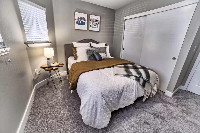 Bedroom with modern decor and large windows at The Arden Apartments