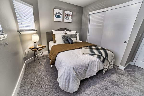 Bedroom with modern decor and large windows at The Arden Apartments