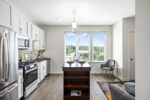 Sleek modern kitchen with island at Avidor Omaha Apartments featuring stainless steel appliances and quartz countertops