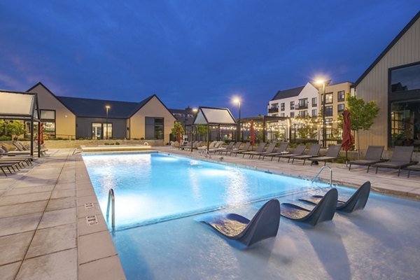 Modern outdoor pool with sun loungers at Novel Daybreak Apartments