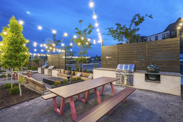 Outdoor grill area with modern seating and greenery at Novel Daybreak Apartments
