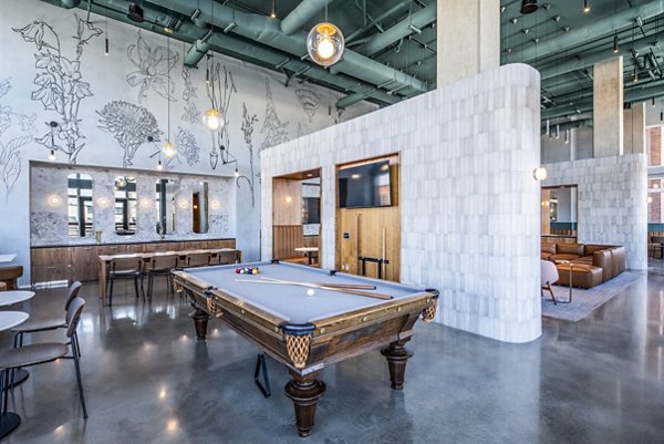 Clubhouse game room with pool table and modern seating at Otis Apartments