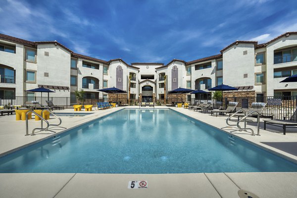Resort-style outdoor pool at The Riley Apartments with sleek loungers and lush landscaping, offering a luxury living experience