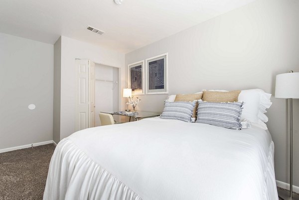 Cozy bedroom with stylish decor and large window in Parcside Townhomes Apartments