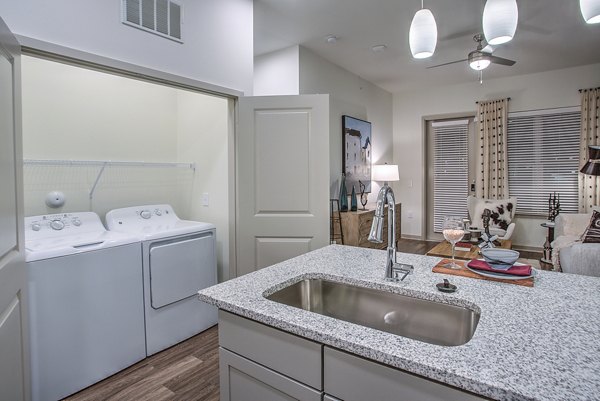 Modern laundry room with high-efficiency washers and dryers at McKinney Terrace Apartments, luxury living by Greystar