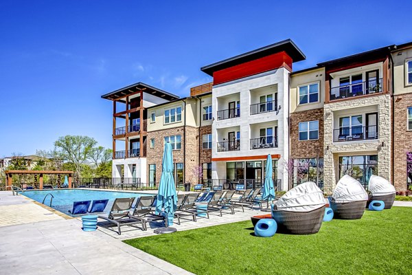 Luxurious poolside view at McKinney Terrace Apartments with umbrella-shaded lounge chairs and sparkling water for relaxation