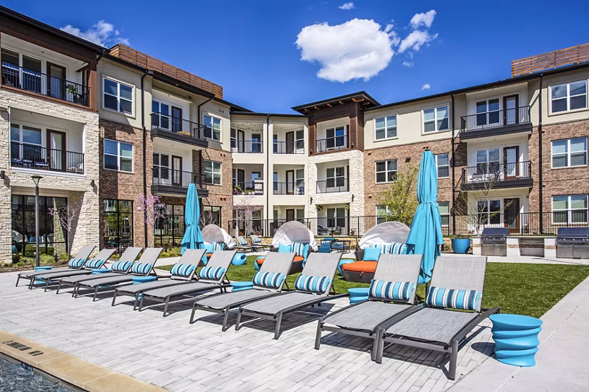 Pool patio with lounge chairs and umbrellas at McKinney Terrace Apartments offering luxury living spaces