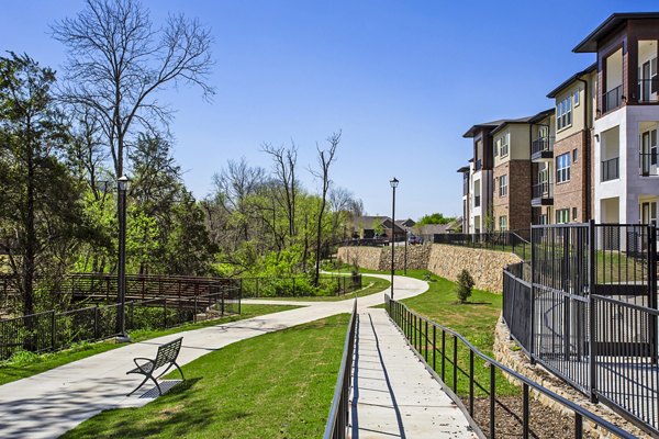 Walking trail surrounded by lush greenery at McKinney Terrace Apartments