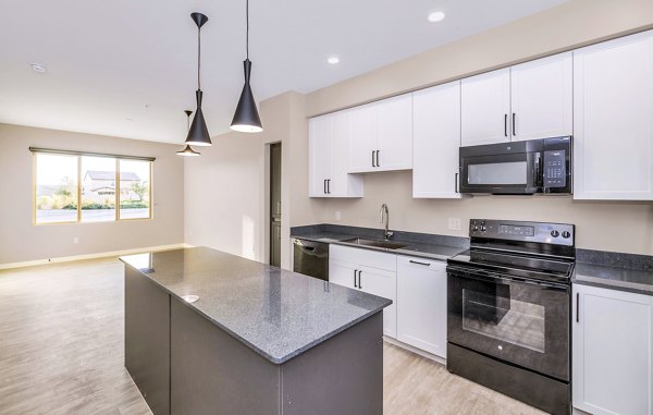 Modern kitchen with stainless steel appliances at The Premiere at Eastmark Apartments, featuring sleek countertops and ample storage