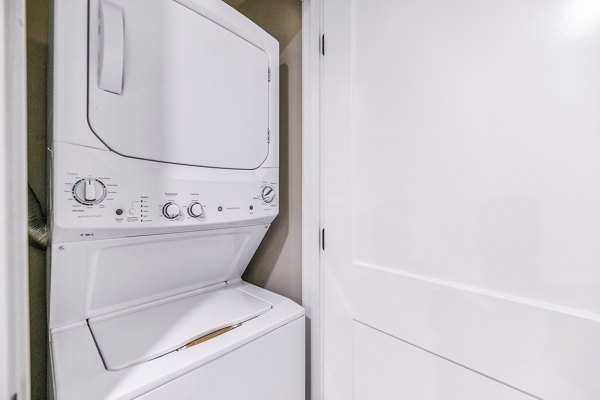 Laundry room with modern machines and ample folding space at The Premiere at Eastmark Apartments