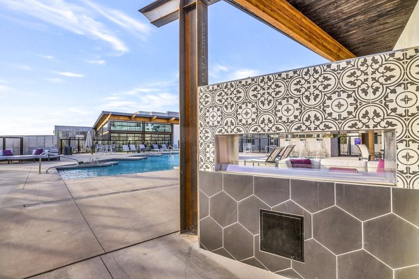 Grill patio area at The Premiere at Eastmark Apartments with modern outdoor seating and lush landscaping, ideal for social gatherings