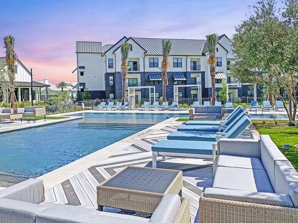 Sunlit outdoor pool at Vineyard Apartments with lush surroundings and lounge chairs