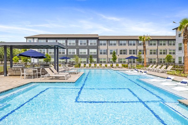 Modern pool area at Ltd Med Center Apartments with loungers and lush landscaping, perfect for relaxation and leisure