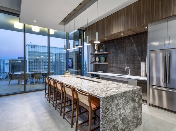 Clubhouse kitchen featuring modern appliances and spacious seating at Stanza Little Italy Apartments