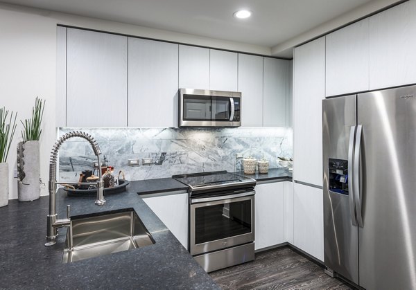 Modern kitchen with stainless steel appliances in Stanza Little Italy Apartments