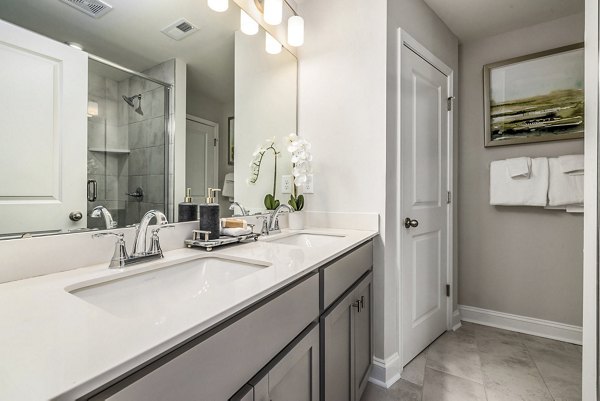 Modern bathroom featuring marble counters and sleek fixtures at ABODE at Parkside Apartment Townhomes