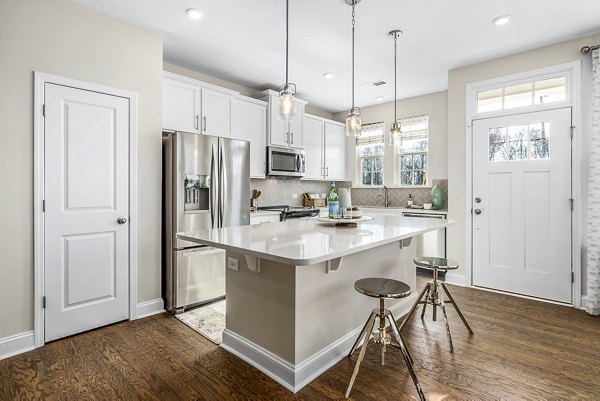 Modern kitchen featuring stainless steel appliances and granite countertops in ABODE at Parkside Apartment Townhomes