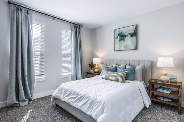 Bedroom featuring modern decor and large windows at The Grove at Coastal Grand Apartments