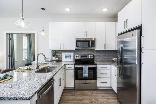 Modern kitchen with stainless steel appliances and granite countertops at The Grove at Coastal Grand luxury apartments