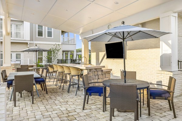 Spacious pool and patio area at The Grove at Coastal Grand Apartments with comfortable seating and lush landscaping