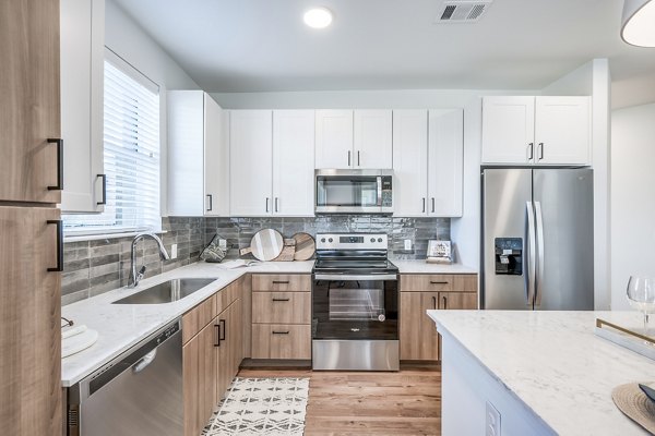 Modern kitchen featuring stainless steel appliances and granite countertops at Starling at Bridgeland Apartments