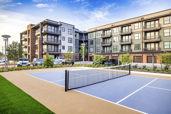 Outdoor tennis court surrounded by lush landscapes at Starling at Bridgeland Apartments