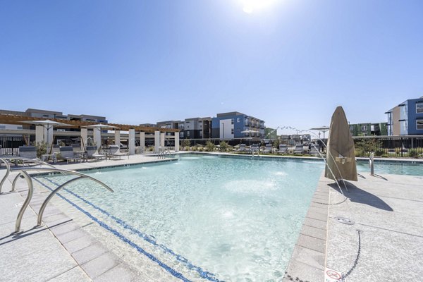 Sunlit outdoor pool with lounge chairs at FLATZ 520 Apartments, a luxury Greystar property