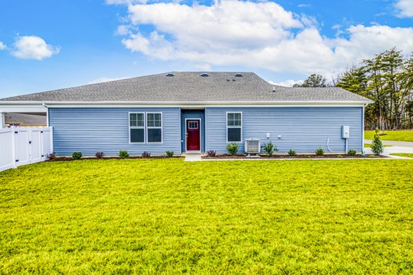 Charming single-story house with blue siding and a red door in a lush grassy yard