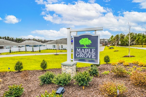 Maple Grove sign surrounded by lush landscaping and pathways in a vibrant garden setting