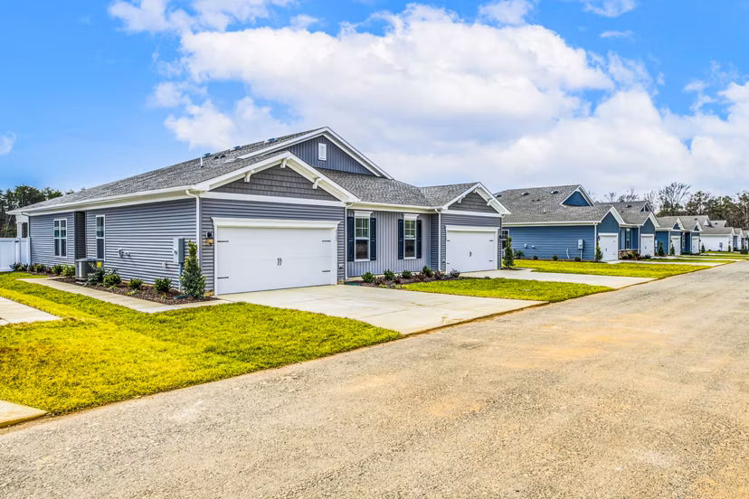 Single-story luxury apartments with garages and manicured lawns in a tranquil community setting
