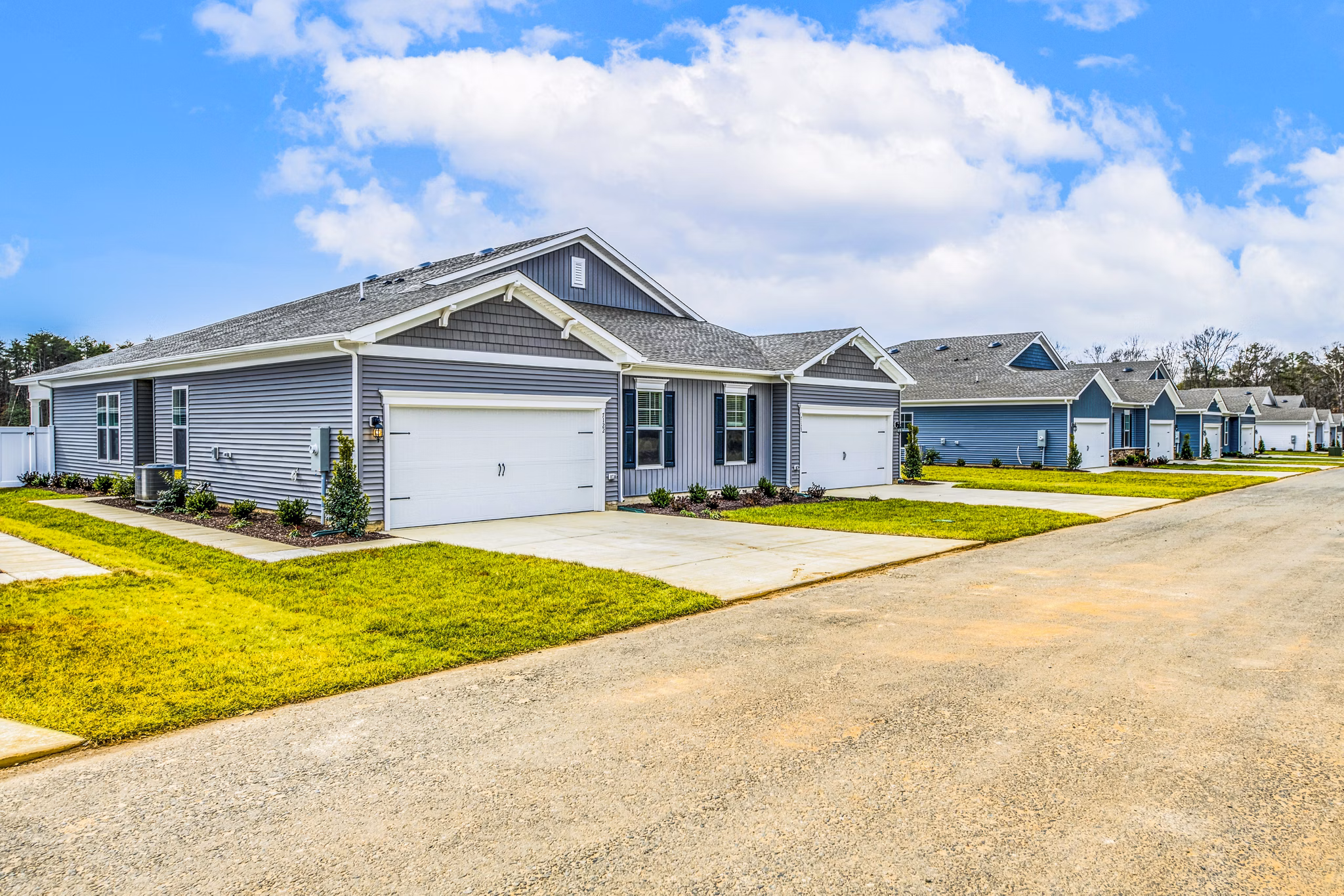 Single-story luxury apartments with garages and manicured lawns in a tranquil community setting