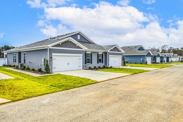 Single-story luxury apartments with garages and manicured lawns in a tranquil community setting