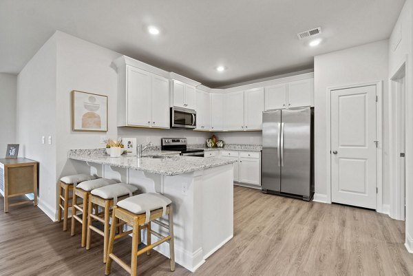 Modern kitchen featuring stainless steel appliances and granite countertops at Maple Grove Apartments