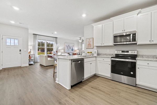 Modern kitchen with stainless steel appliances and marble countertops at Maple Grove Apartments