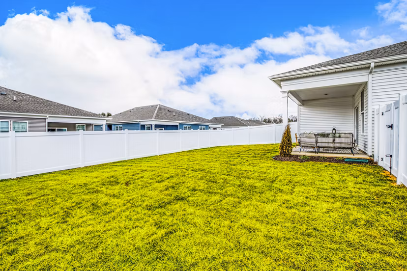 Grassy backyard with white fence and charming porch at luxury apartments