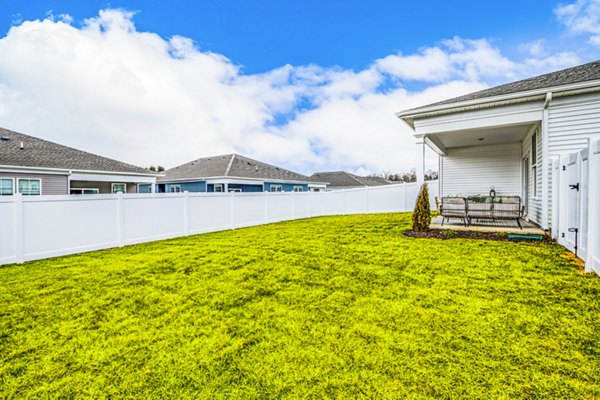 Grassy backyard with white fence and charming porch at luxury apartments