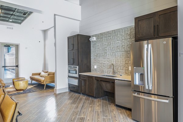 Clubhouse kitchen featuring modern appliances and island seating at Birchway Hudson Oaks Apartments