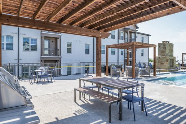 Grill area with modern patio seating at Birchway Hudson Oaks Apartments